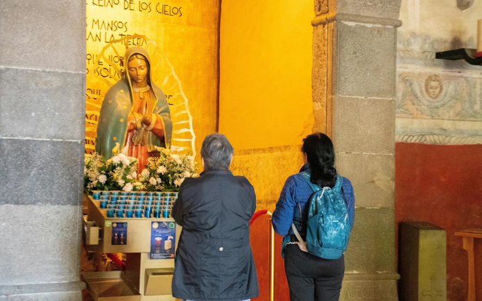 Visitors observing a religious statue in a Cuernavaca church during Mexico City: Cuernavaca & Taxco Day Tour.