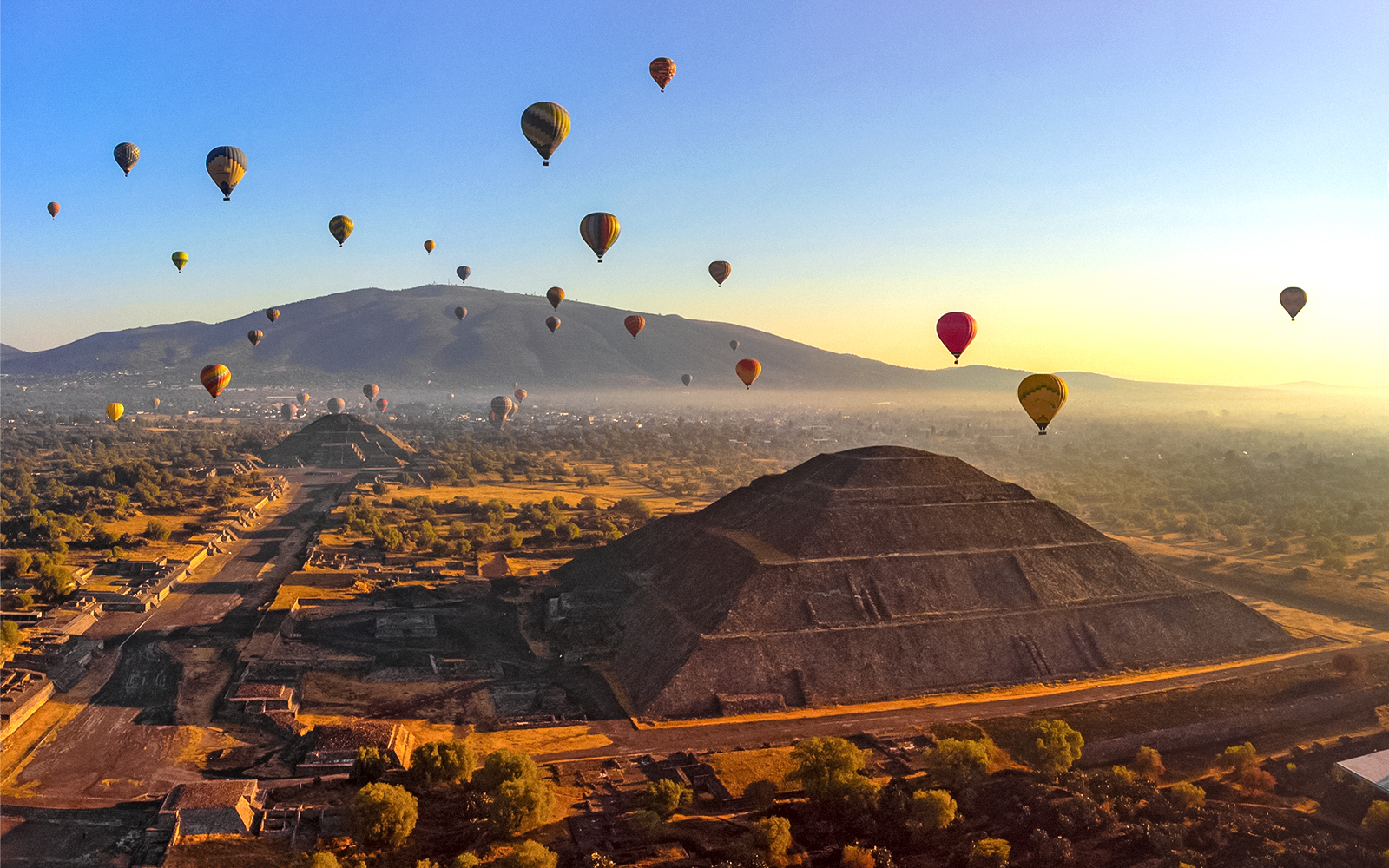 Hot air balloons floating above Teotihuacan pyramids, Mexico.