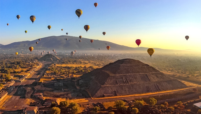 Hot air balloons floating above Teotihuacan pyramids, Mexico.