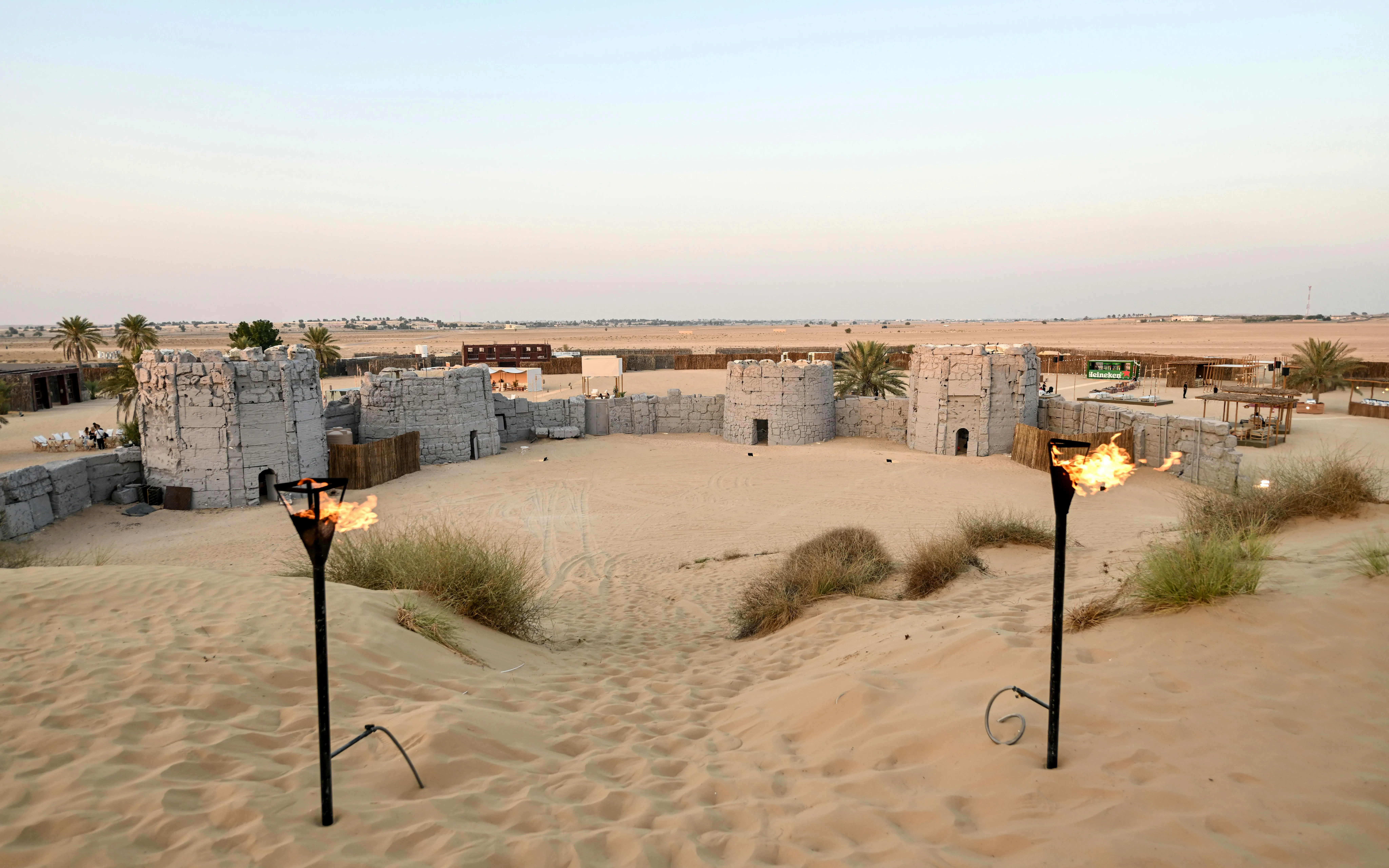 Desert camp with stone structures and torches in Dubai desert safari.