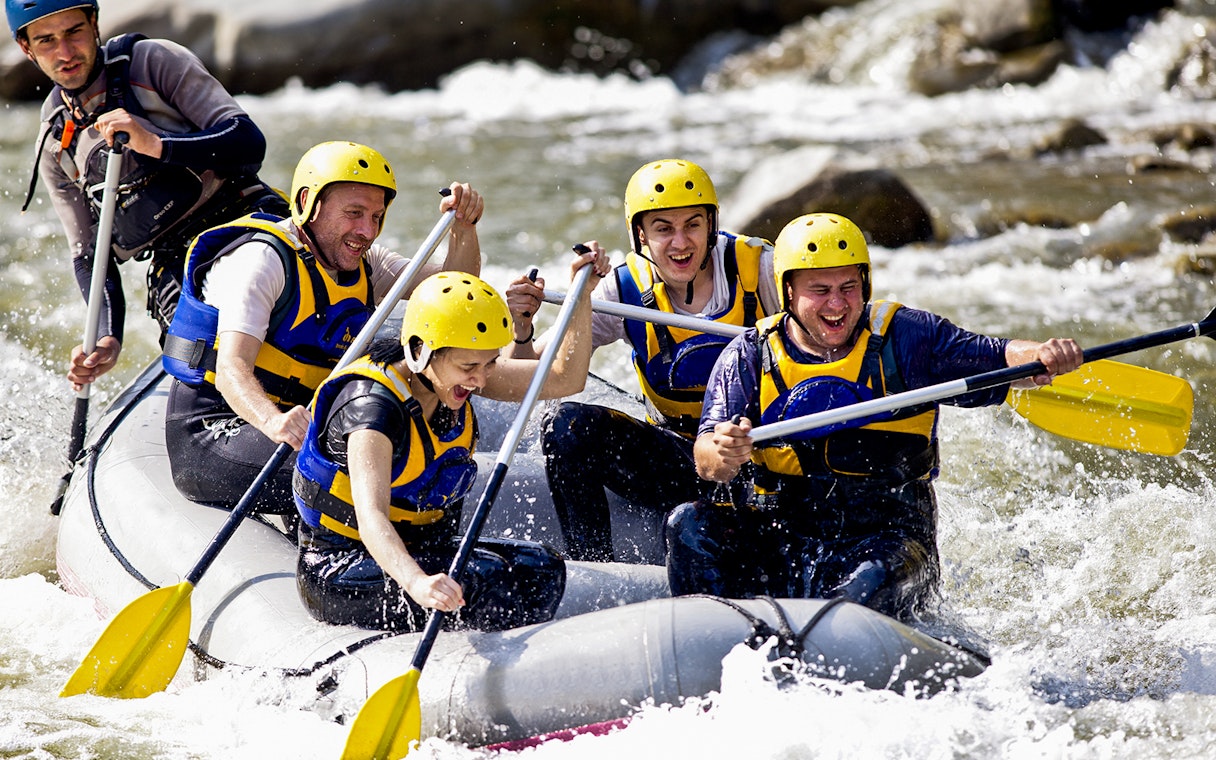 Group rafting on a river in Antalya, wearing helmets and life jackets.