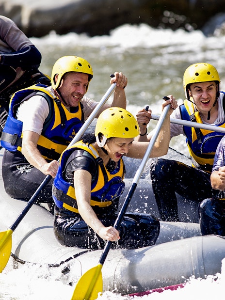 Group rafting on a river in Antalya, wearing helmets and life jackets.