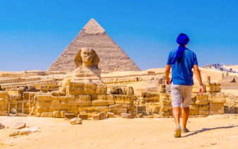 Person walking towards the Sphinx and Pyramid at Giza Complex, Egypt.