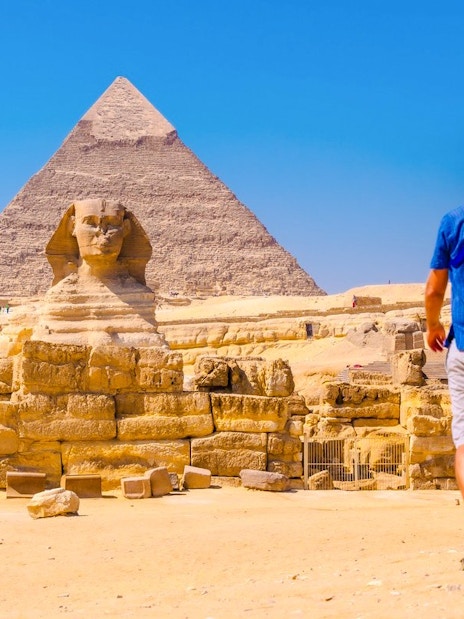 Person walking towards the Sphinx and Pyramid at Giza Complex, Egypt.