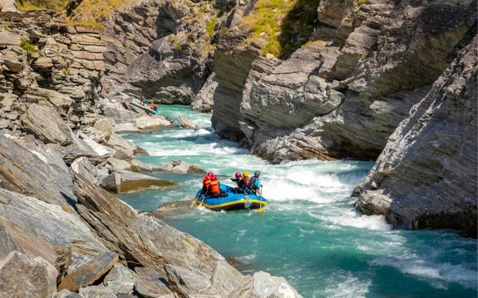 Whitewater rafting on Shotover River, Queenstown, navigating rocky canyon.