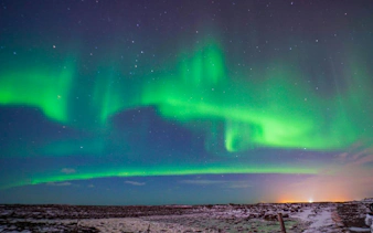 Northern Lights over snowy landscape during Reykjavik Super Jeep tour.