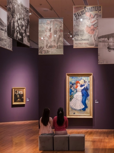 Impressionist paintings displayed in National Gallery Singapore with visitors observing art.