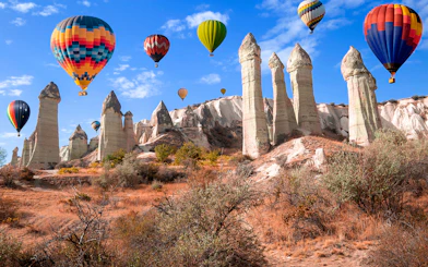 Hot air balloons over rock formations in Love Valley, Cappadocia, Turkey.