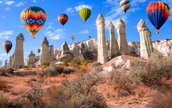 Hot air balloons over rock formations in Love Valley, Cappadocia, Turkey.