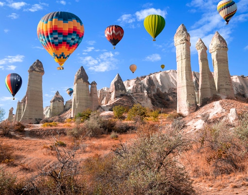 Hot air balloons over rock formations in Love Valley, Cappadocia, Turkey.