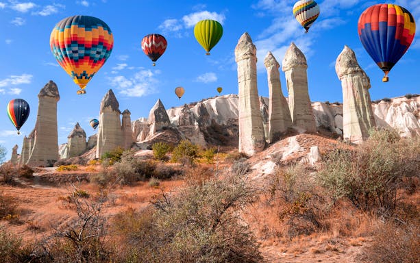 Hot air balloons over rock formations in Love Valley, Cappadocia, Turkey.