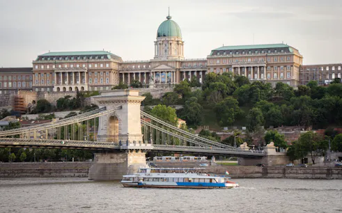 Budapest cruise boat passing Chain Bridge with Buda Castle in the background.