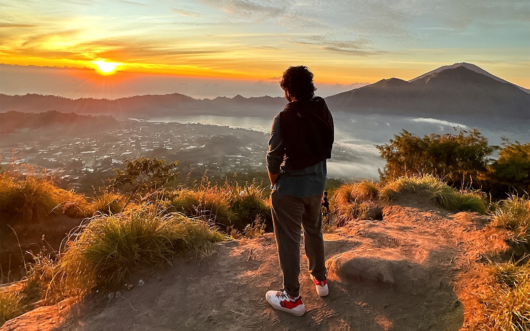 Person watching sunrise over Mount Batur during a jeep tour in Bali.