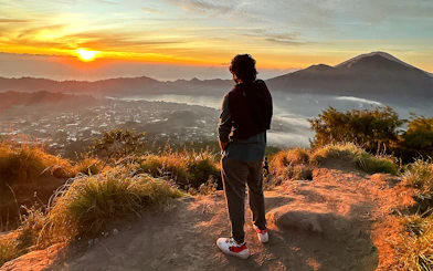 Person watching sunrise over Mount Batur during a jeep tour in Bali.