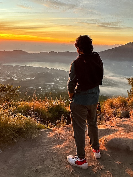 Person watching sunrise over Mount Batur during a jeep tour in Bali.