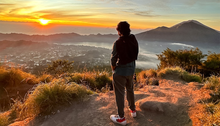 Person watching sunrise over Mount Batur during a jeep tour in Bali.