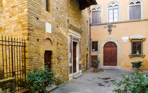 Piazza del Limbo courtyard with historic stone buildings and arched doorways in Florence, Italy.