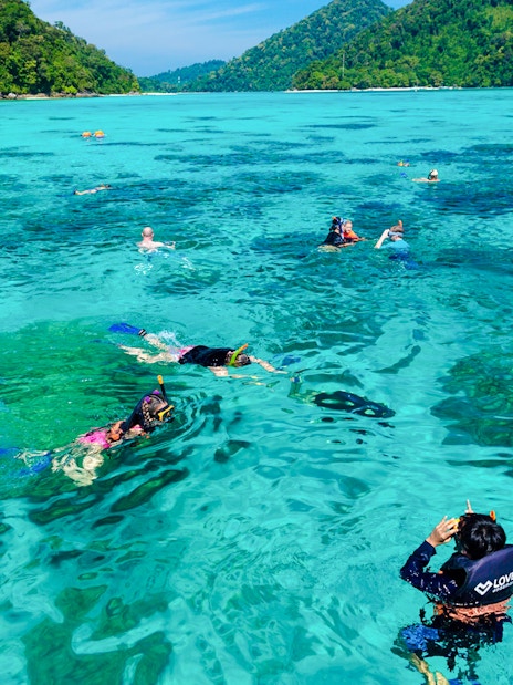 Tourists snorkeling in clear turquoise waters of Surin Islands, Thailand.