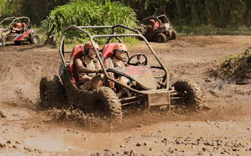 Buggy ride through muddy terrain in Bali with lush greenery in the background.
