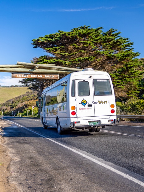 Van on Great Ocean Road under wooden archway, Australia.
