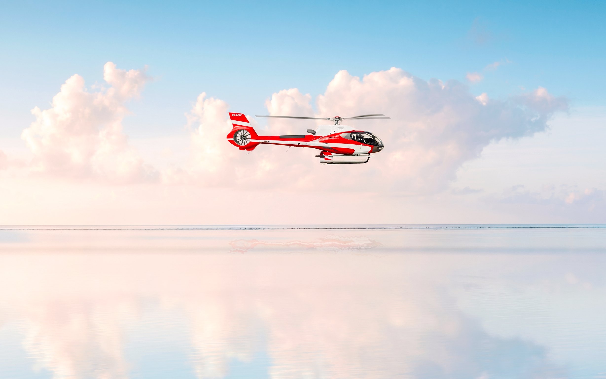 Private helicopter flying over the sea with clouds in Monaco.