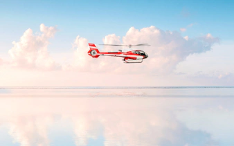 Private helicopter flying over the sea with clouds in Monaco.