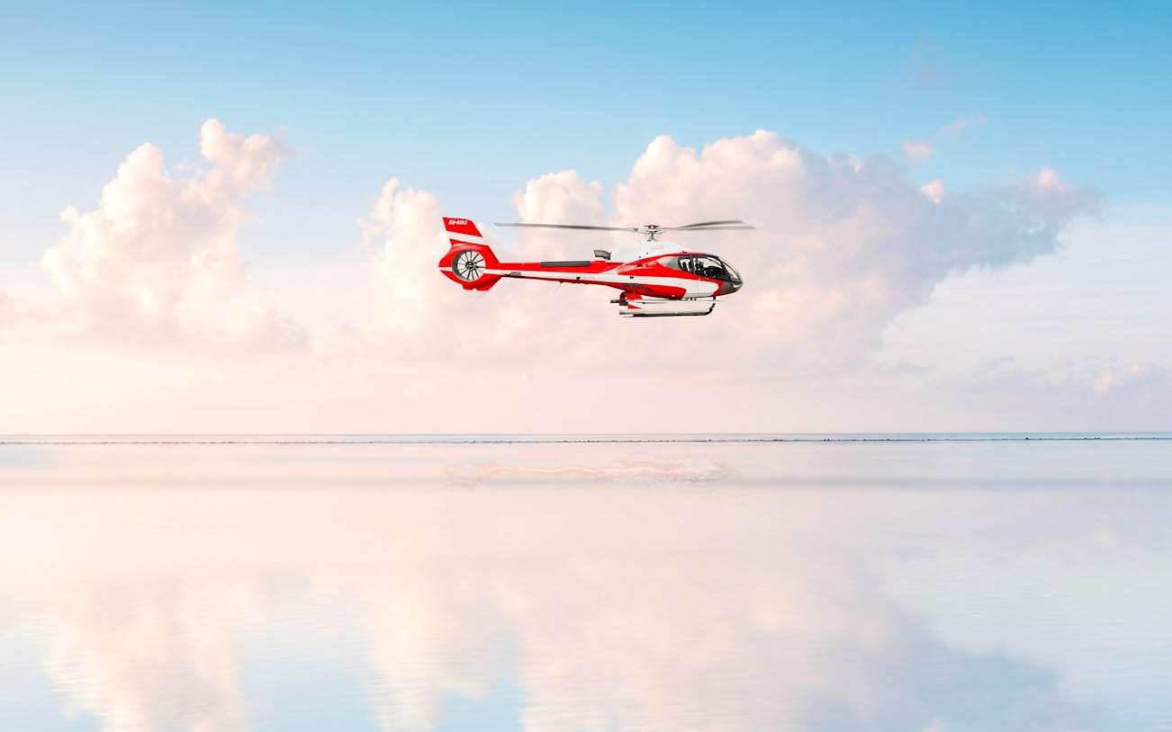 Private helicopter flying over the sea with clouds in Monaco.