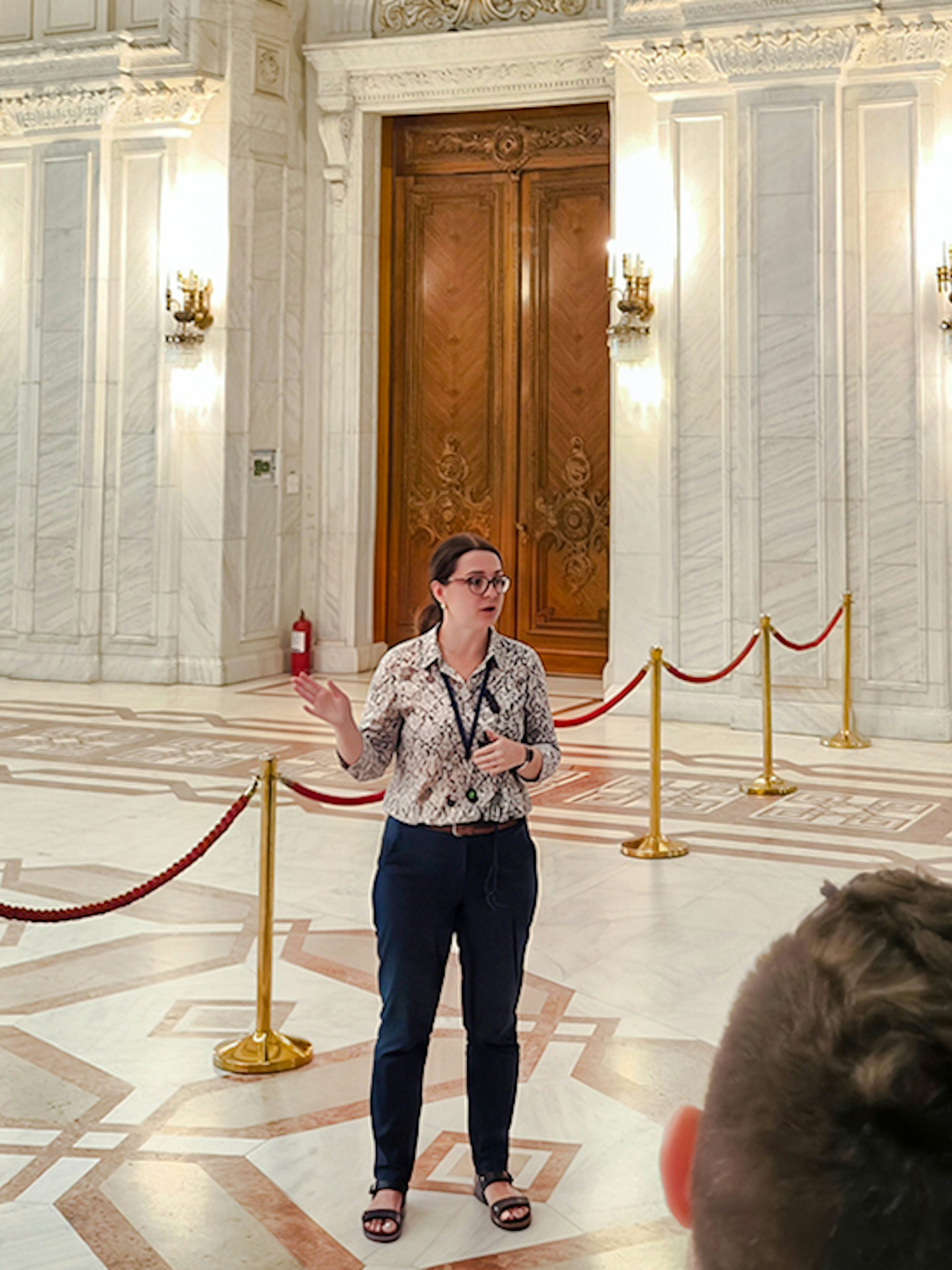 Tour guide speaking inside the ornate hall of the Palace of Parliament, Bucharest.
