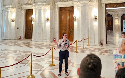 Tour guide speaking inside the ornate hall of the Palace of Parliament, Bucharest.