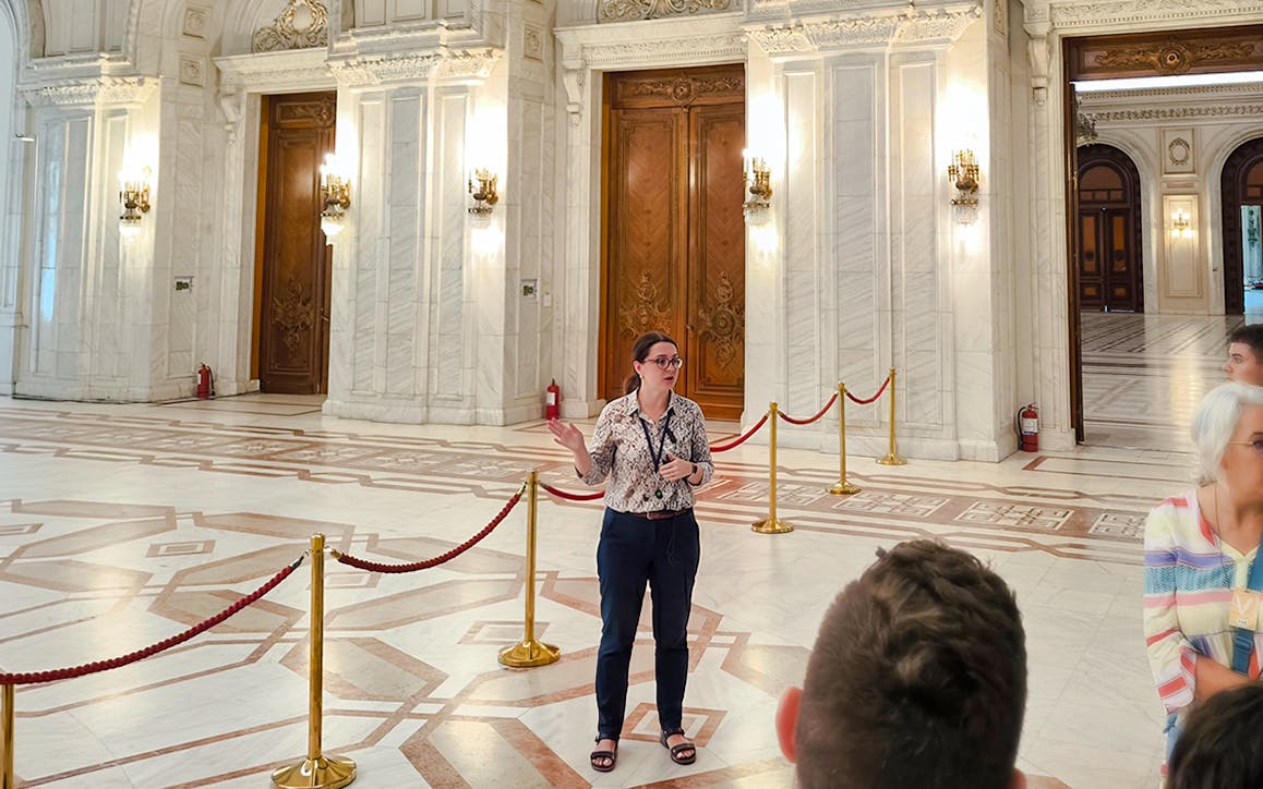 Tour guide speaking inside the ornate hall of the Palace of Parliament, Bucharest.
