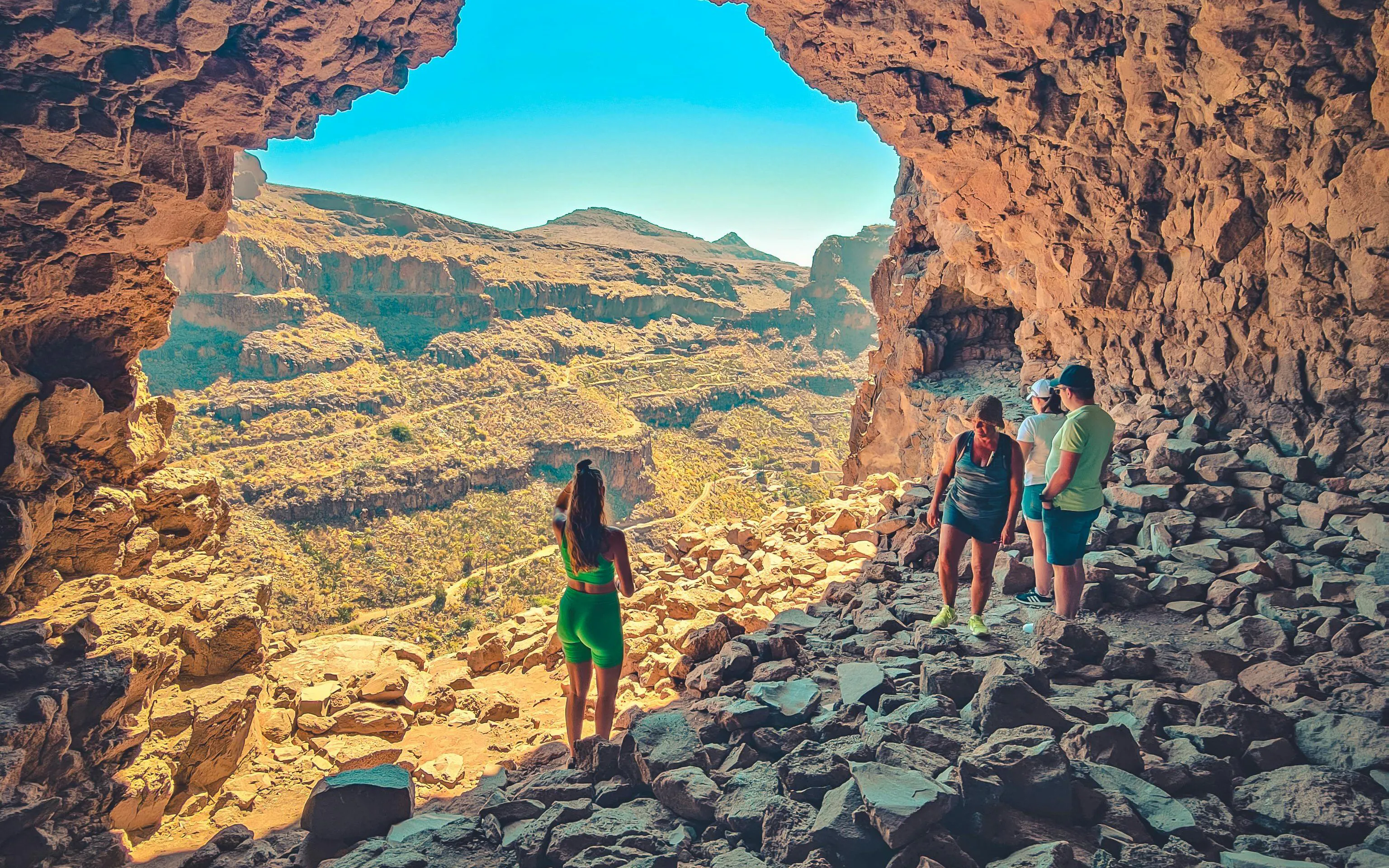 Tourists exploring rocky cave with view of Red Canyon, Gran Canaria.