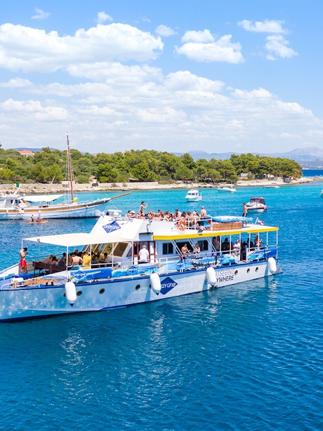 Cruise ship with tourists in Split's Blue Lagoon, surrounded by sailboats and clear blue water.