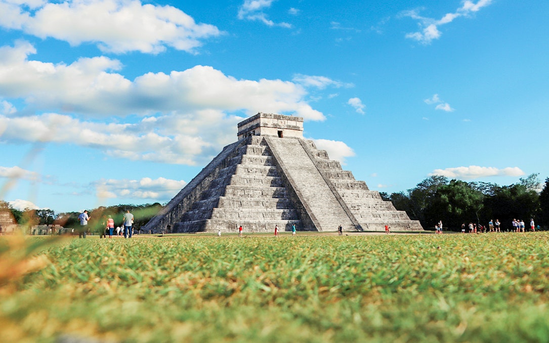 Tourists exploring El Castillo pyramid at Chichen Itza, Mexico.