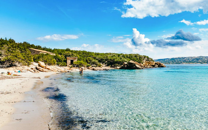 La Maddalena Archipelago beach with clear water and rocky shoreline on a sunny day.