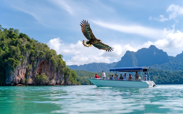 Eagle flying over speedboat with tourists during Langkawi Island hopping tour.
