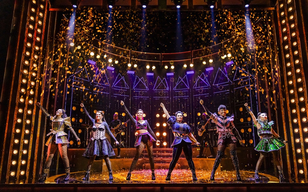 Performers on stage during a musical show with vibrant lighting and costumes.