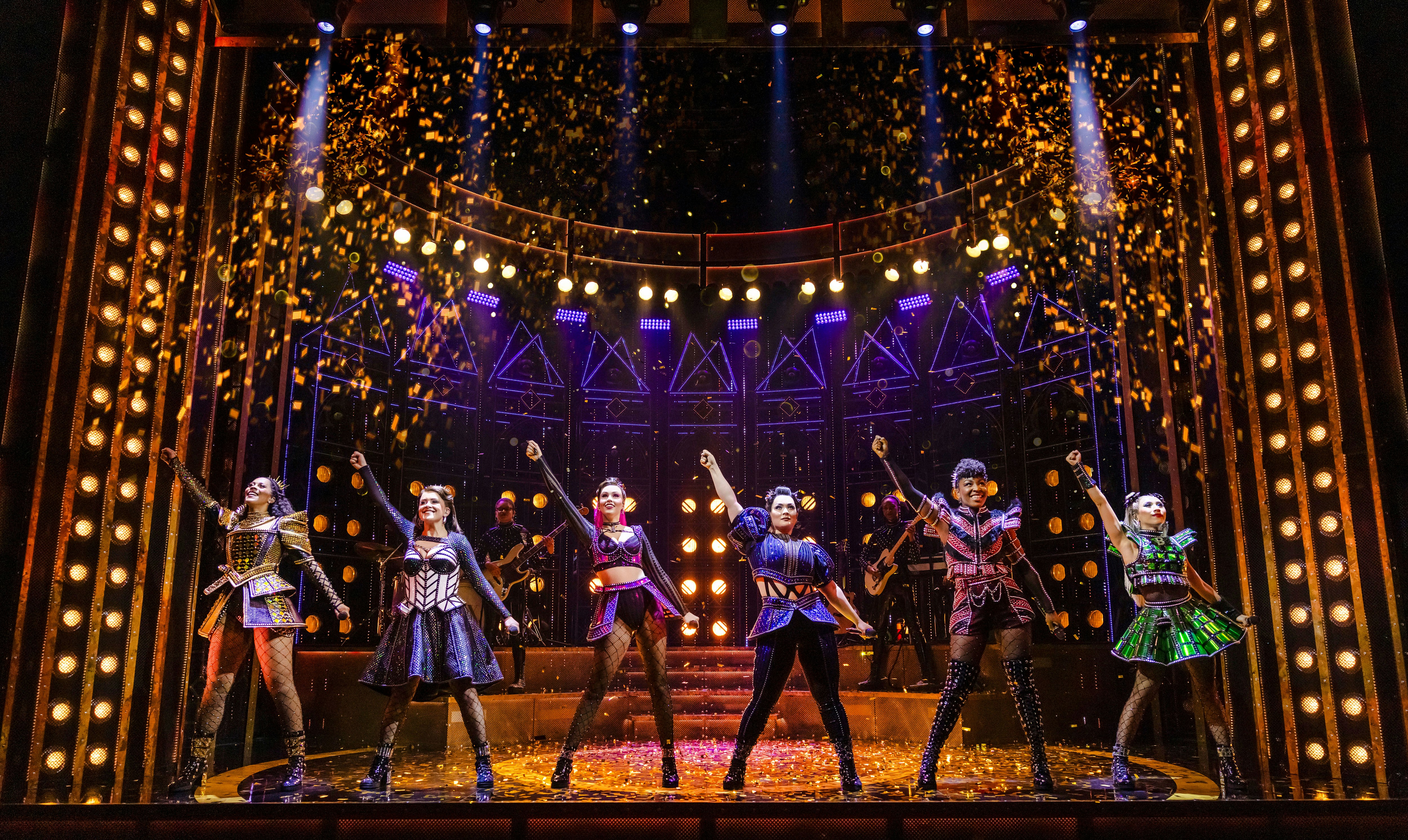 Performers on stage during a musical show with vibrant lighting and costumes.