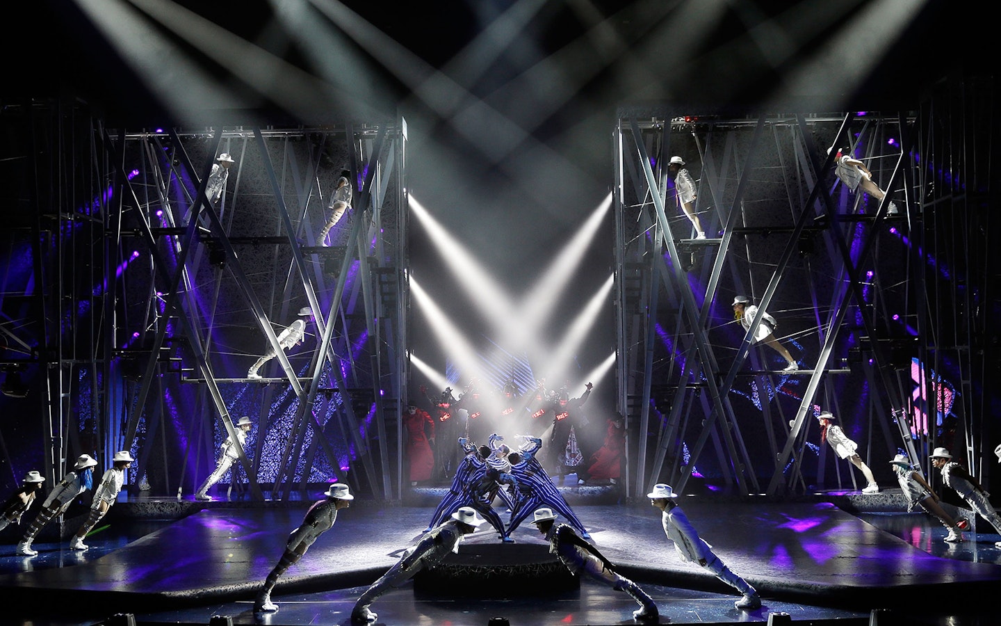 Performers in white suits and hats lean forward on stage during Michael Jackson ONE show.