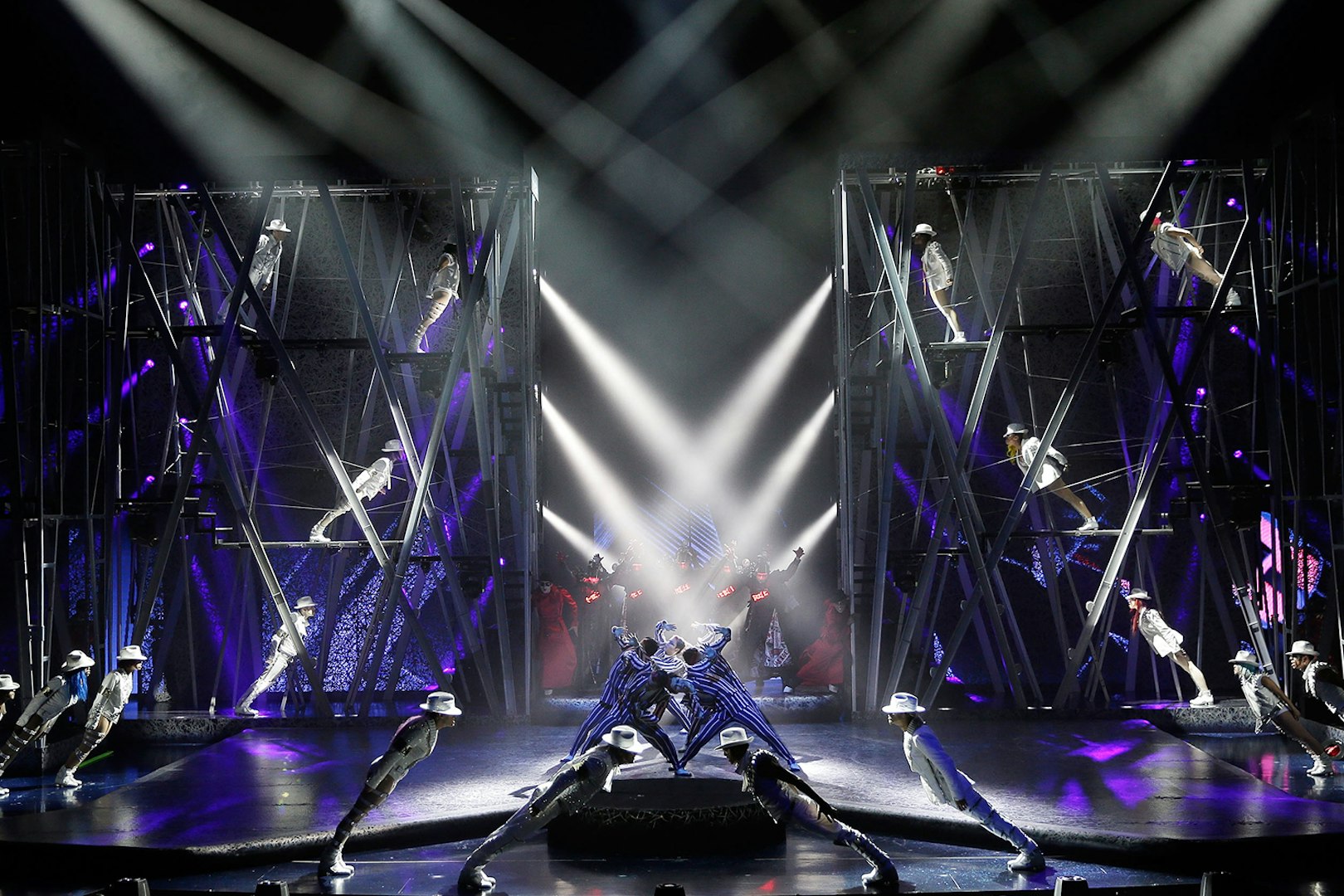 Performers in white suits and hats lean forward on stage during Michael Jackson ONE show.