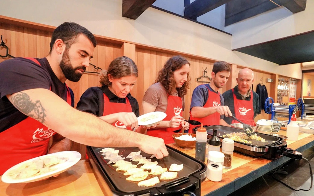Participants cooking gyoza during a Kyoto ramen and gyoza class.