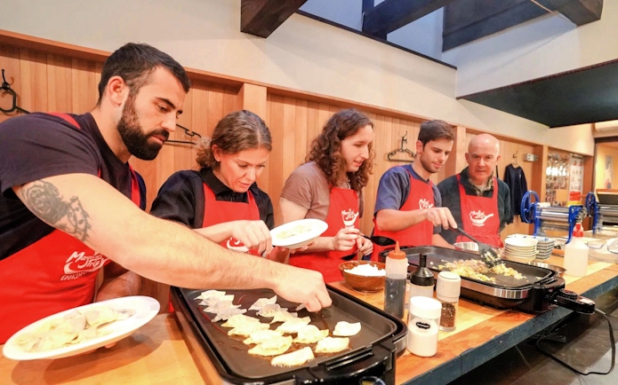 Participants cooking gyoza during a Kyoto ramen and gyoza class.