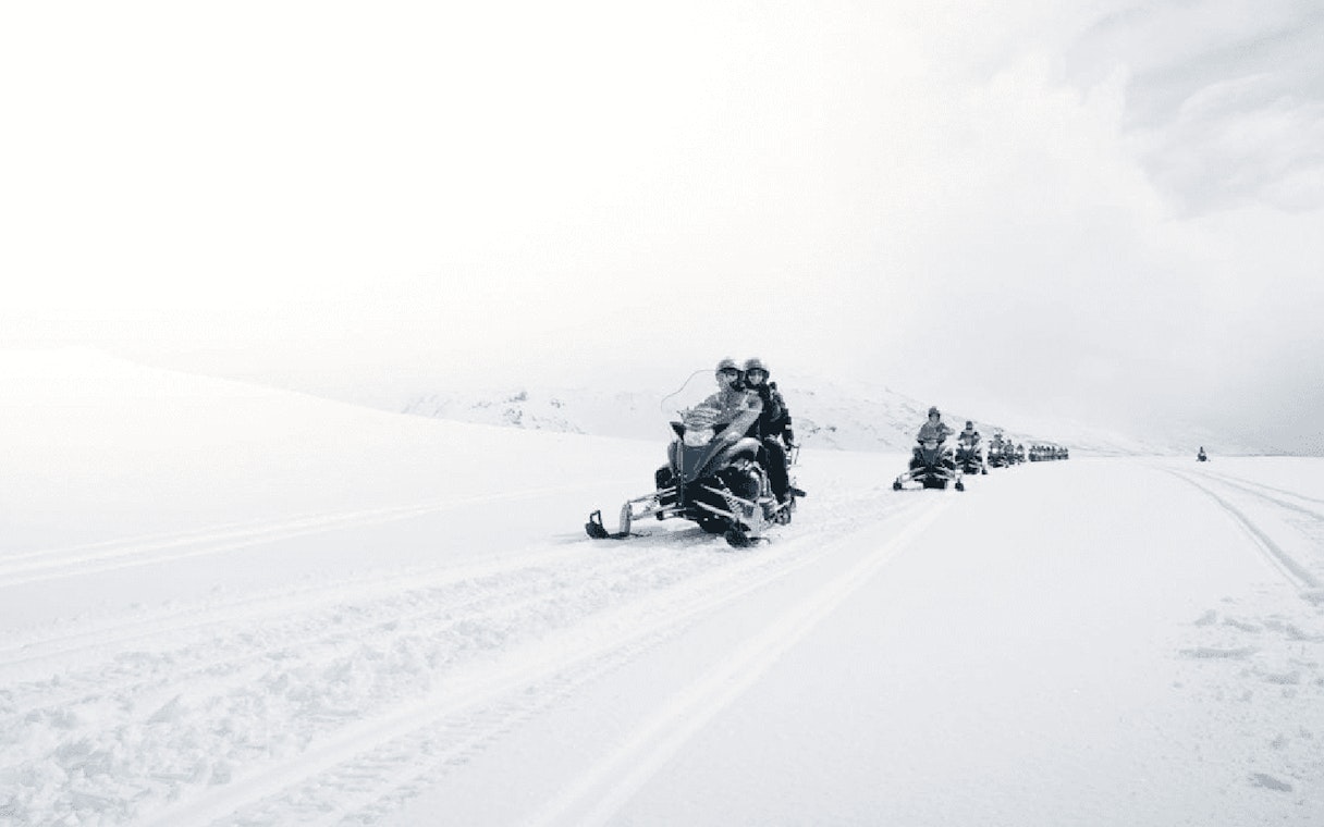 Snowmobilers on glacier during Secret Lagoon hot spring tour in Iceland.