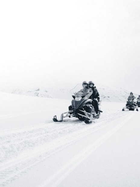Snowmobilers on glacier during Secret Lagoon hot spring tour in Iceland.