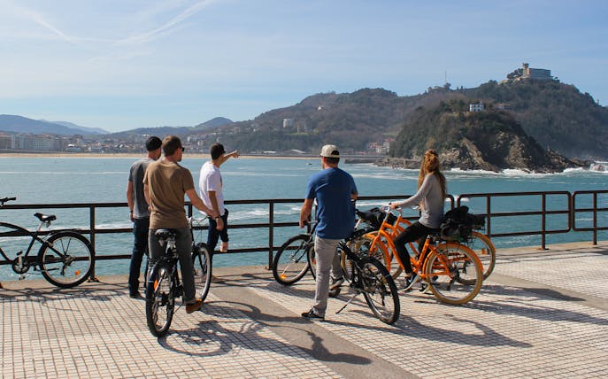 Group on bikes overlooking San Sebastian coastline during a tour.