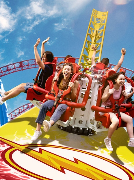 Tourists enjoying the Flash ride at Movie World with vibrant roller coaster tracks.