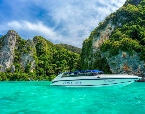 Speedboat on turquoise water near rocky islands in Phi Phi, Thailand.