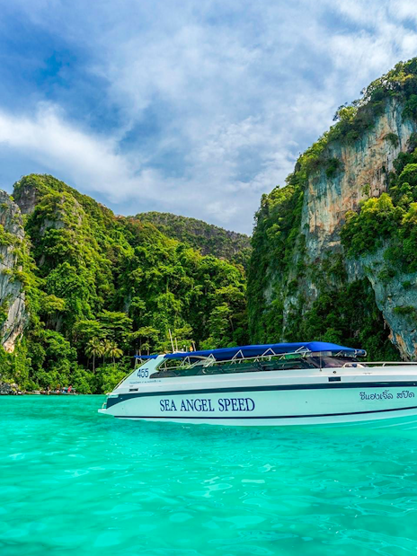 Speedboat on turquoise water near rocky islands in Phi Phi, Thailand.