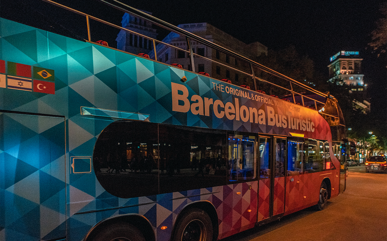 Barcelona Bus Turistic at night on a city street.