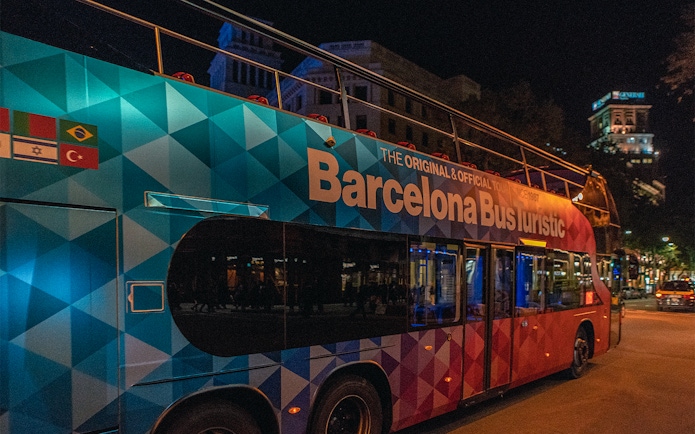 Barcelona Bus Turistic at night on a city street.