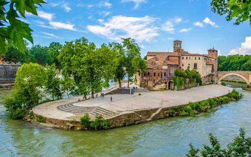 Tiber Island with historic buildings and trees, Rome, viewed from the Tiber River.